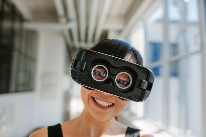 Close up shot of cheerful young woman wearing virtual reality goggle