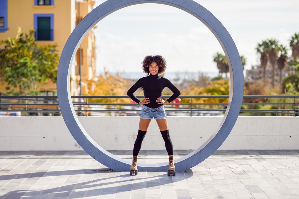 Woman standing in front of circle-shaped sculpture wearing roller-skates
