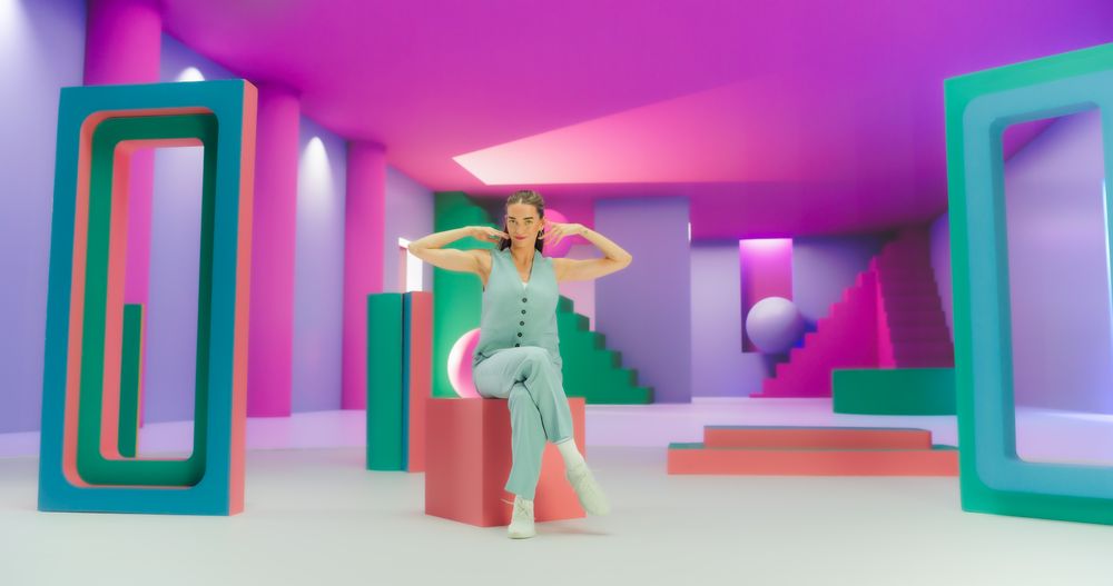 White Woman with Bright Makeup Dancing Energetically and Interacting with Colorful Geometric Abstract Environment. Creative Young Female Happily Performing Dance with Dynamic Movement