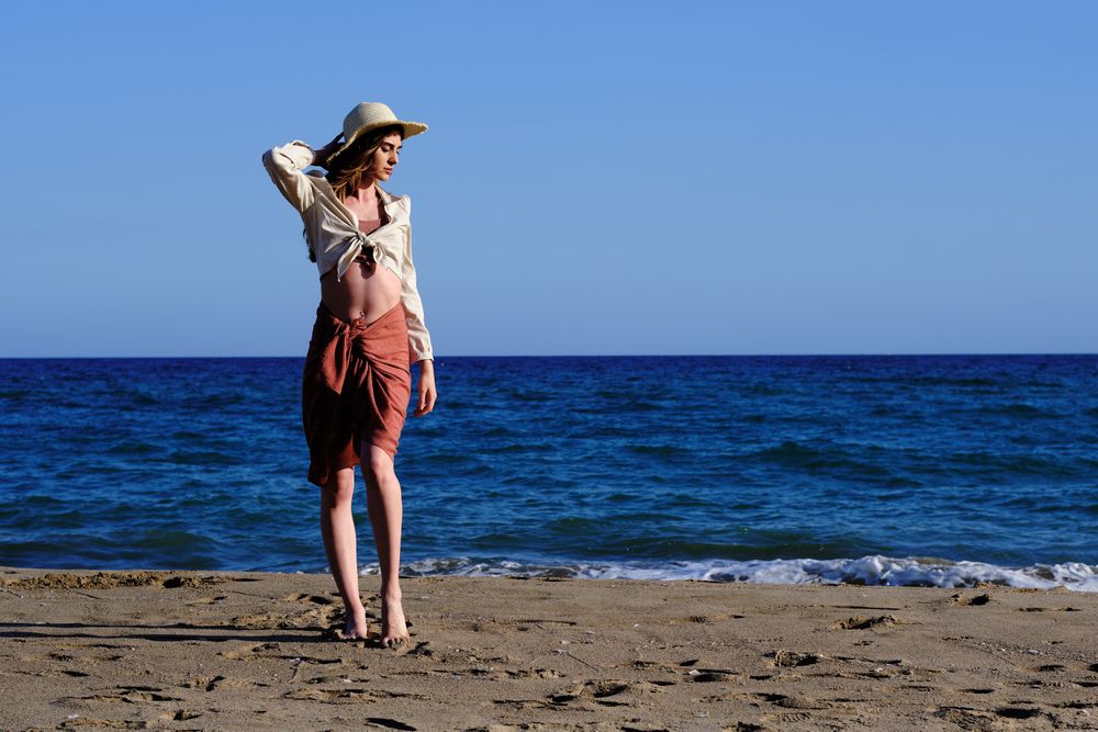 A fashion model with a hat at the beach before sunset
