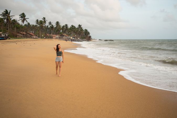 Woman in beachwear walking on sand barefoot