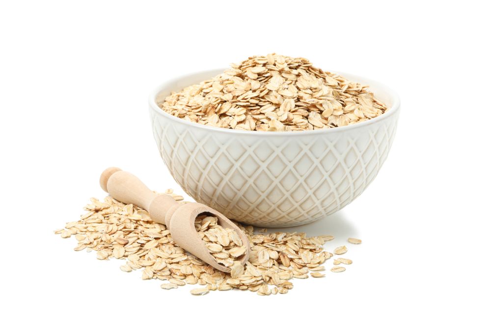 Bowl and scoop with oatmeal flakes isolated on plain background