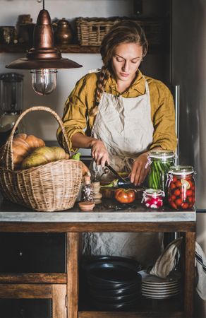 Young woman in rustic kitchen cutting eggplant