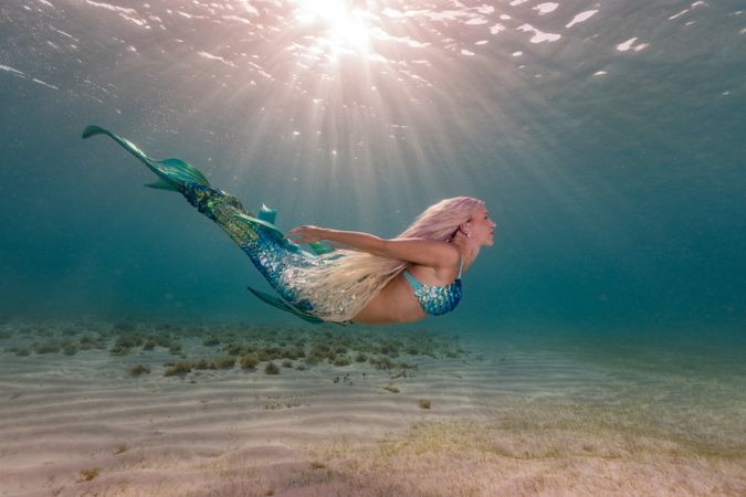 Blond fairytale female mermaid swimming underwater