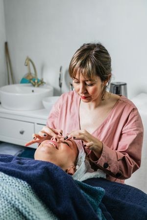 Smiling masseuse doing massage for woman in spa salon