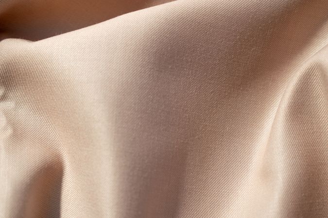 Close up silk shiny light brown fabric background texture.