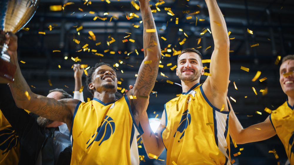 Multiethnic Basketball Players Celebrate Championship Victory with Hugs, Jumping, Holding the Trophy High.