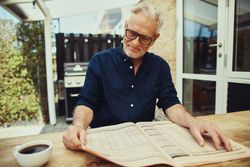Mature man enjoying reading the newspaper outside