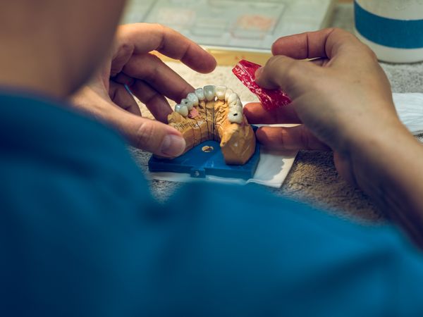 Crop technician applying soft material on dental prosthetics