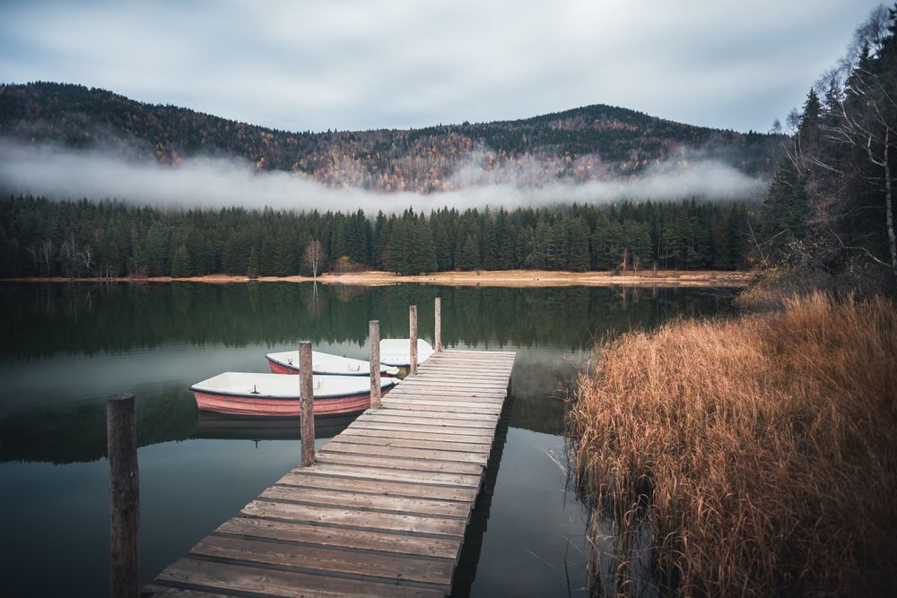Three dinghies near wooden dock on still lake