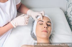 Aesthetician's hands injecting botox into woman's forehead in a beauty salon 41lM1L