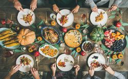 Thanksgiving Day table with turkey, pumpkin pie, roasted vegetables, fruit and wine