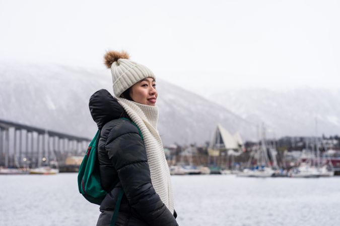 Asian female tourist in warm wear at snowy field near city