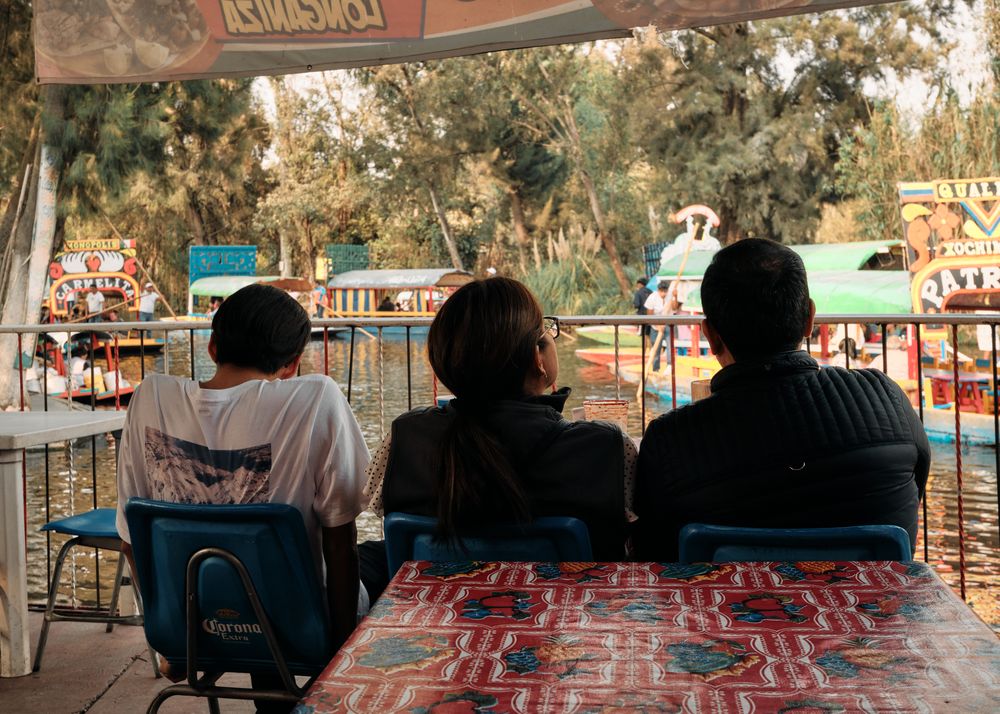 Back of three males looking out at view of colorful boats in tourist destination