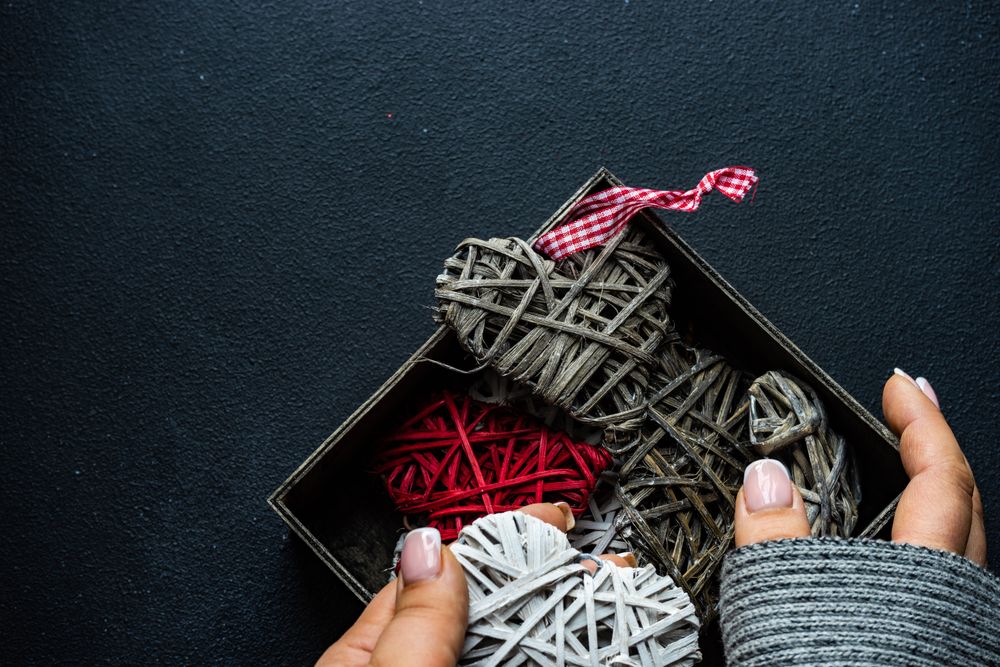 Hands holding box of thatched heart decorations 