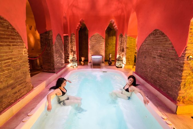Female friends sitting across from each other in luxurious spa