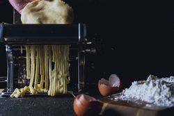 Person preparing noodles with pasta machine