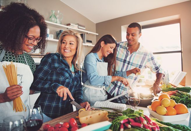 Happy friends smiling while cooking in a bright kitchen.