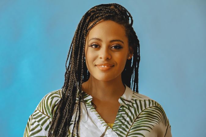 Portrait of confident and content female with long braided hair in printed leaf shirt