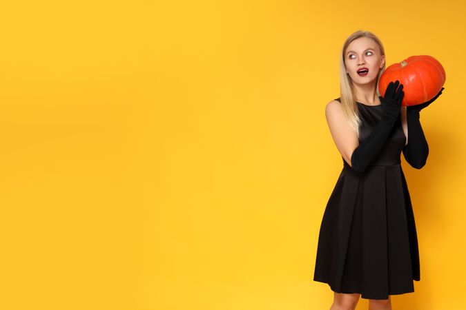 Concept of Halloween, young woman on yellow background
