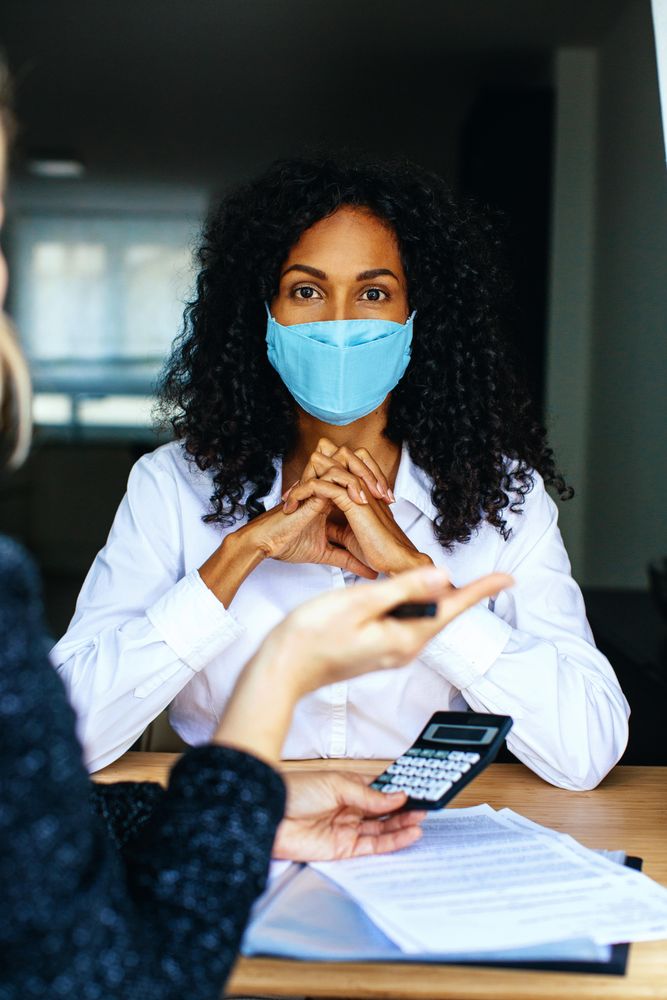 Woman going through paperwork and numbers with a colleague wearing a facemask