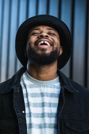 Smiling Black hipster man in hat looking up