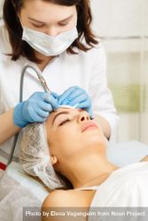 Woman having beauty treatment with machine on her forehead, vertical 4Zzxy4