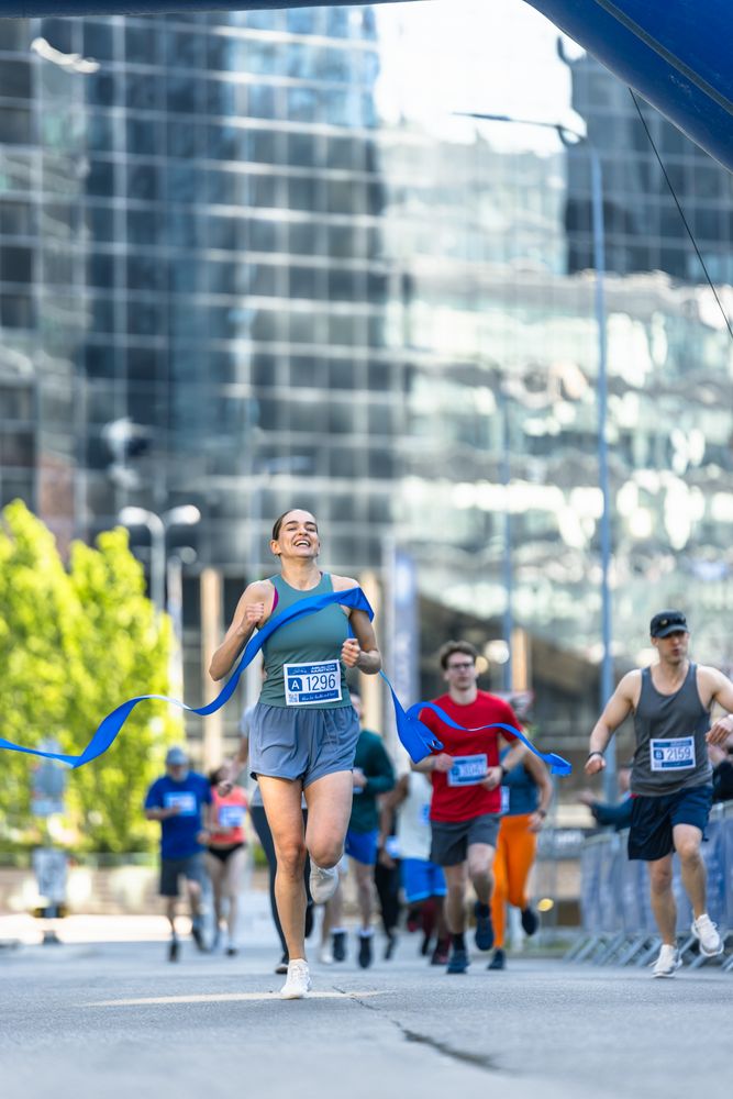 Portrait of Athletic Female Jogger Crossing the Finish Line in Marathon Race with the Audience Cheering.