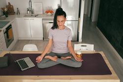 Woman meditating with beer near laptop