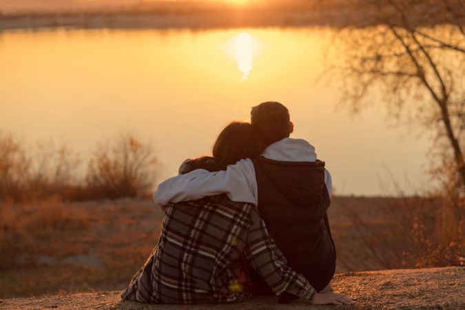 Couple sitting sunset lake