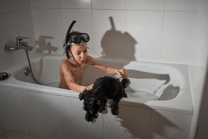 Boy with dog in bathtub