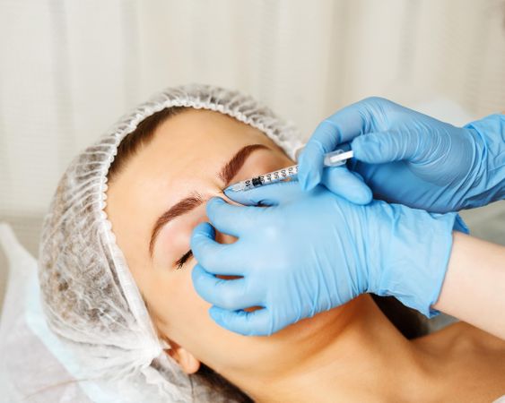 Cosmetologist at med spa injecting between eyes on face of female client