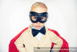 Unsmiling blond boy wearing airplane goggles and cape 4dd7n4