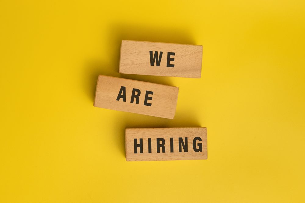we are hiring words on wooden blocks isolated on yellow background