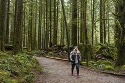 Woman with her hands in her pockets hiking in forest