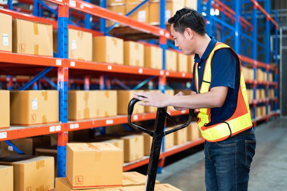 Man in front of boxes of stock on shelves in store house