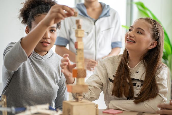 Two girls building a tower with wooden toy at school