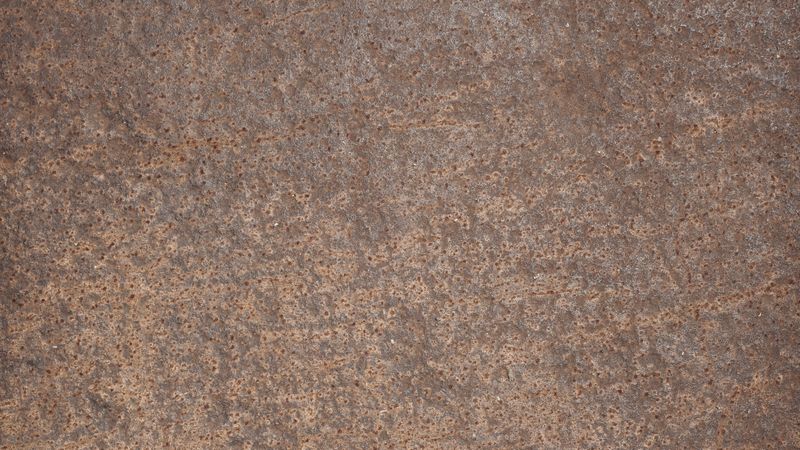 Rusted steel surface with fine pits and rough corroded metallic texture
