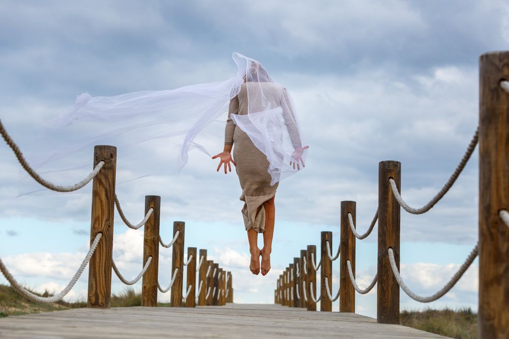 Woman with textile posing in air on footbridge