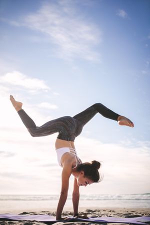 Flexible woman doing yoga handstand pose