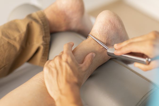 An older man is treated in a physiotherapy clinic with a hook and diacutaneous fibrolysis technique on the foot and ankle area
