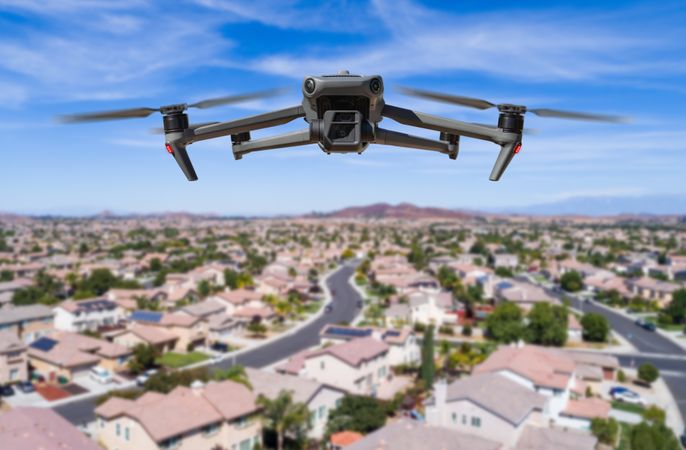 Unmanned Aircraft System (UAV) Quadcopter Drone In The Air Over Residential Neighborhood.