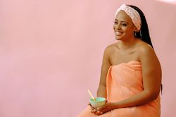 Portrait of smiling woman in spa towel with bowl of product, copy space