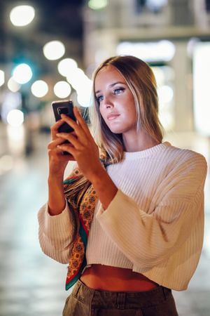 Chic woman with scarf in hair taking photo with phone