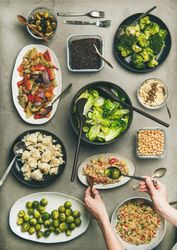 Vegan dinner table setting with healthy dishes in plates on concrete table
