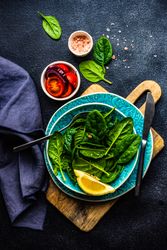 Looking down at fresh spinach salad with lemon slice