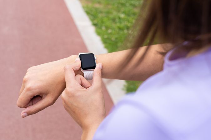 Woman checking a sport smartwatch for running workout outdoors