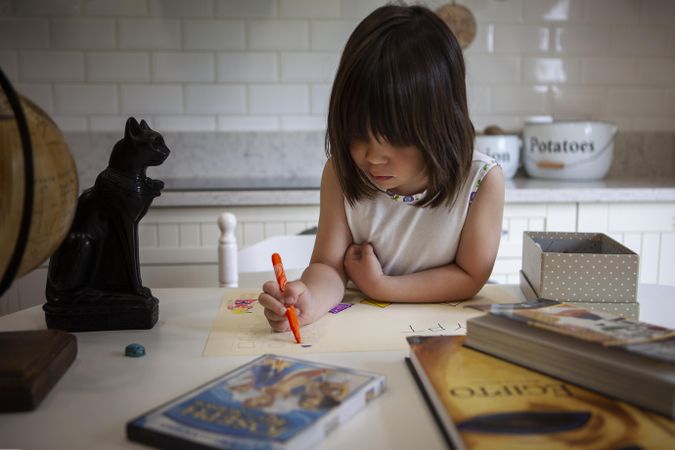 Girl indrawing on paper in kitchen