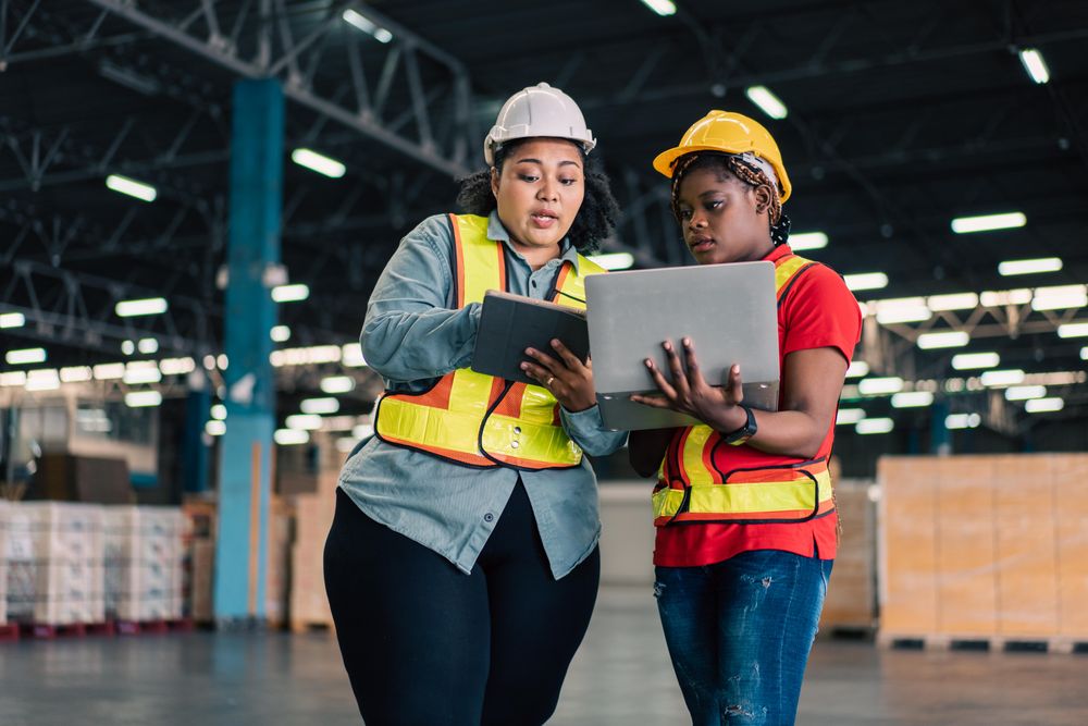 Female co workers discussing stock together in distribution center