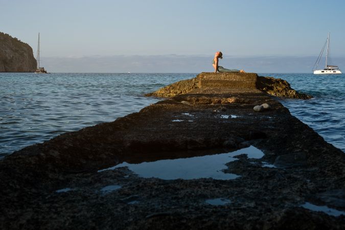 Young woman practicing yoga at seaside